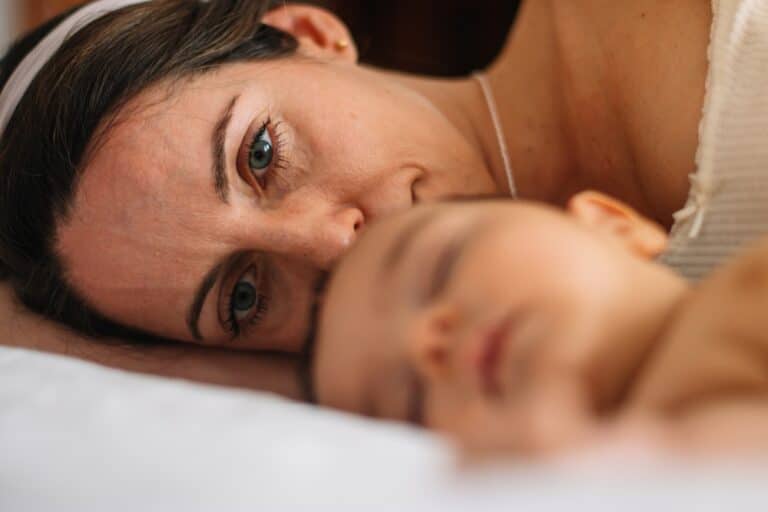 Tired woman with baby sleeping in foreground