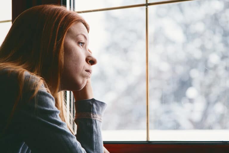 Woman sad looking out a winter window