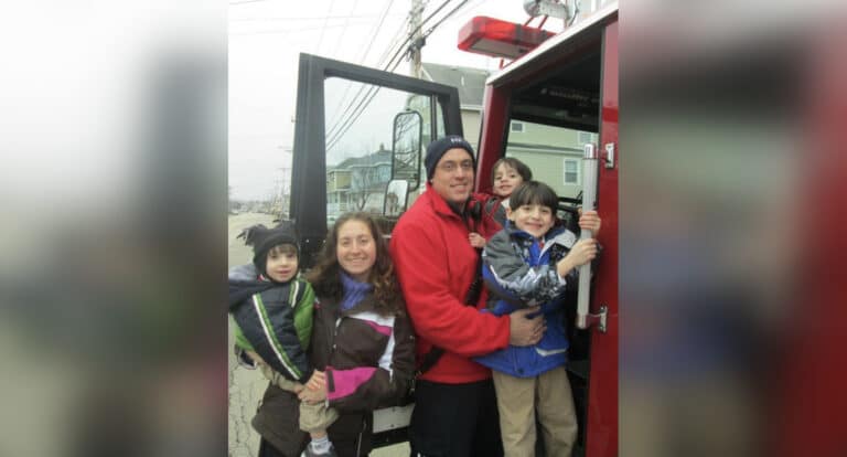 Family by fire truck wearing winter clothing