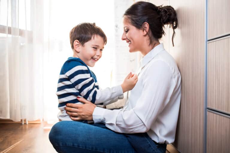 Mother and son sit on floor together and smile