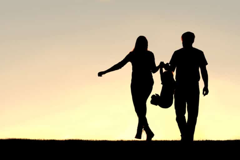 Silhouette of family swinging child between two parents