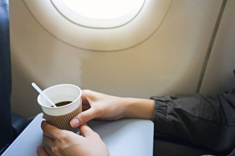Hands holding coffee on airplane