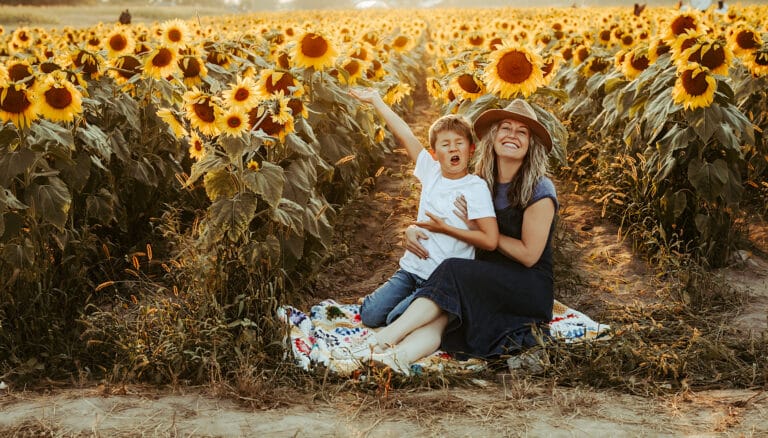 Woman with son in sunflower field, color photo