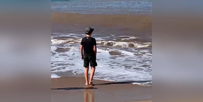 Boy walking in the ocean surf