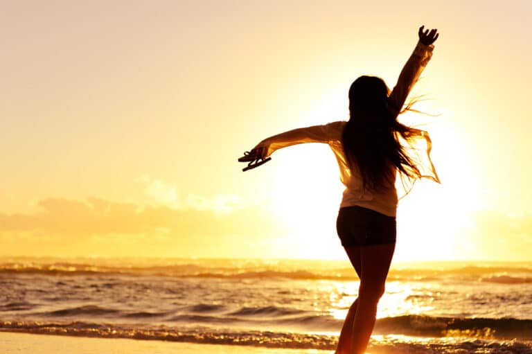 Woman dancing on beach at sunrise