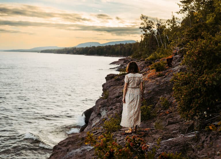 Young girl in a dress on a a rocky, lake shoreline, color photo