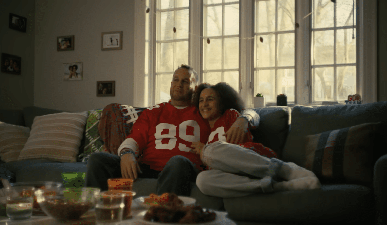 father and daughter cuddled up on the couch watching football