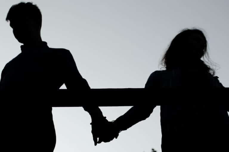 Man and woman holding hands facing away from each other, silhouette