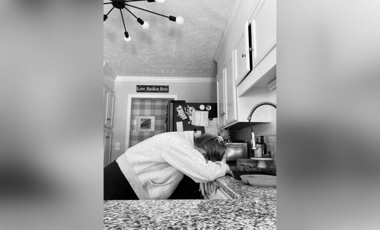 Woman leaning against kitchen counter, black-and-white photo