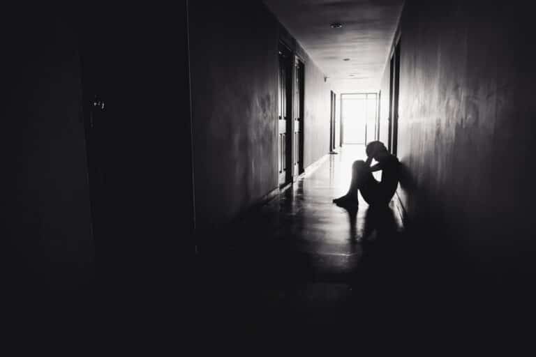 Sad person sitting in darkened hallway, black and white image