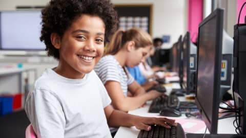 Tween boy smiling in class at computer