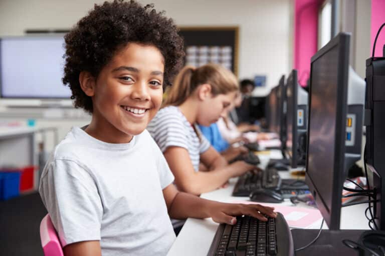 Tween boy smiling in class at computer