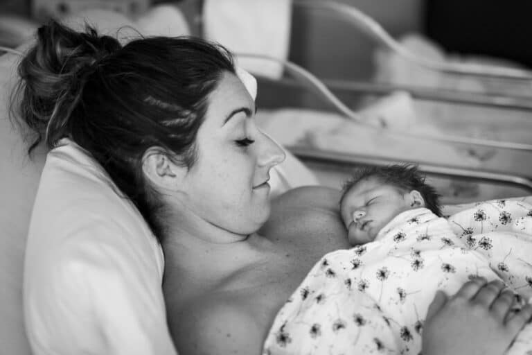 Mother with newborn baby on her chest in hospital bed