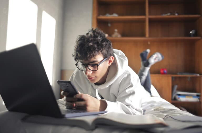 Teen in room studying with computer and smartphone