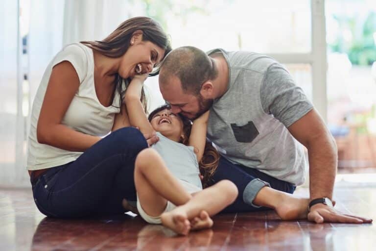 Family of 3 sitting on floor together at home