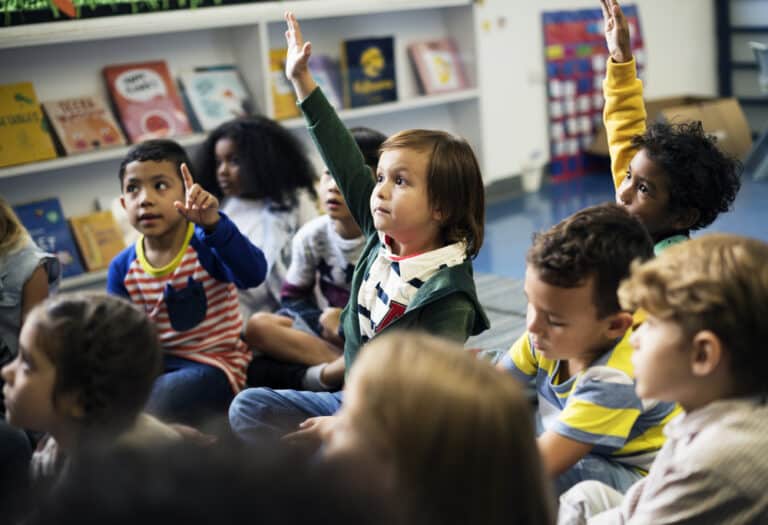 Child raising hand in kindergarten class
