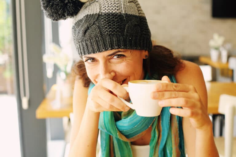 Woman smiling with coffee cup in hand, color photo