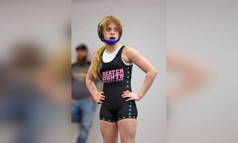 Young female wrestler wearing mouth guard and wrestling singlet