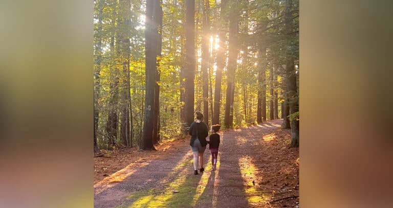 Mother and child walking through forest, color photo