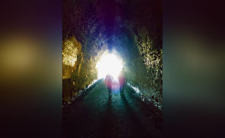 Two people walking down tunnel, color photo