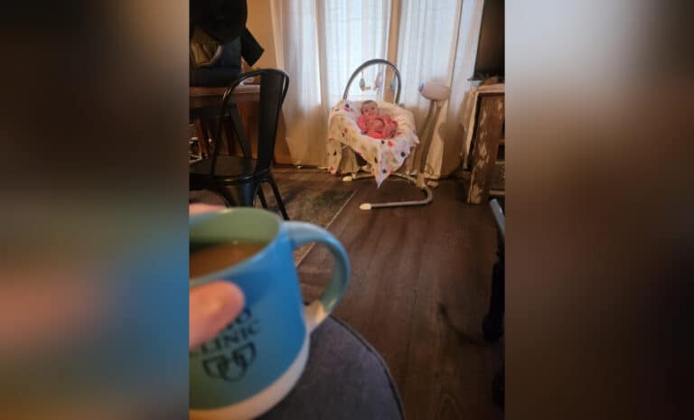 Baby in bouncer next to mama with coffee cup, color photo