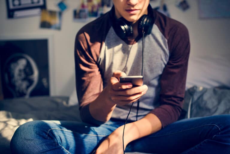 Teen boy holding a smartphone and wearing headphones