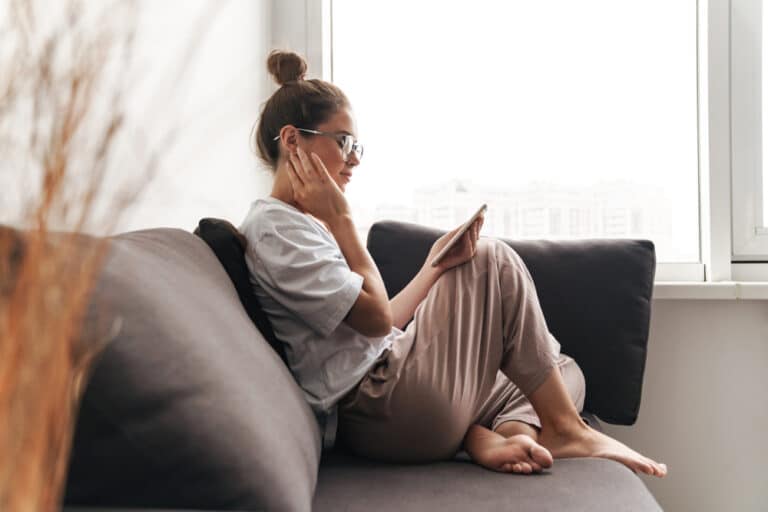 Woman sitting along on couch looking at smartphone