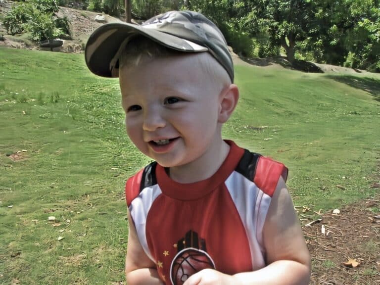 Photo of smiling 2-year-old Colt Catalina in a red shirt and cap