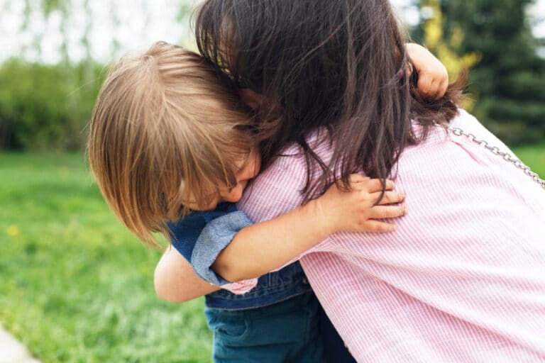 Mother hugging young boy outside