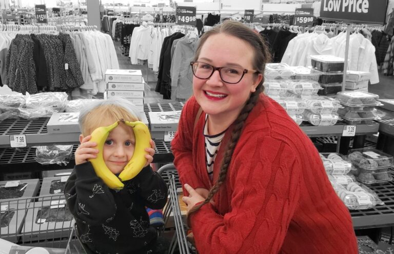 Little boy with bananas on his face posing with mother in store