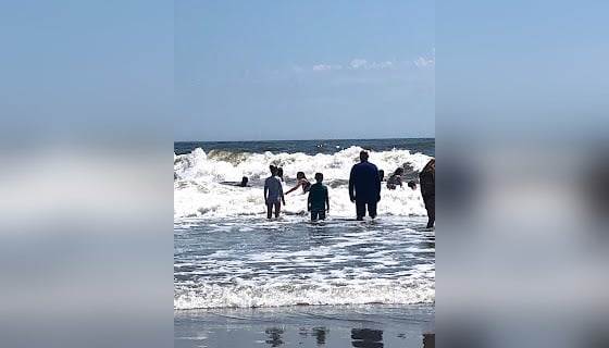 Kids and parents playing in waves at the ocean