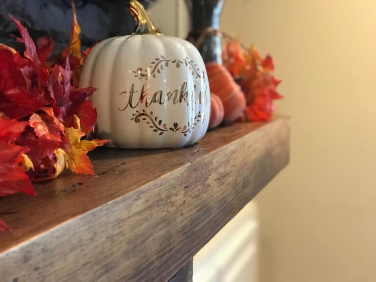 Ceramic pumpkin on hearth that says "thankful"