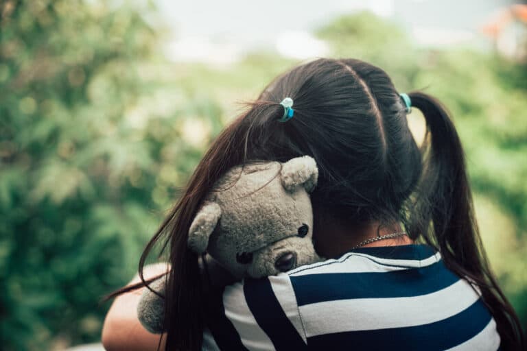 Girl hugging well-loved teddy bear
