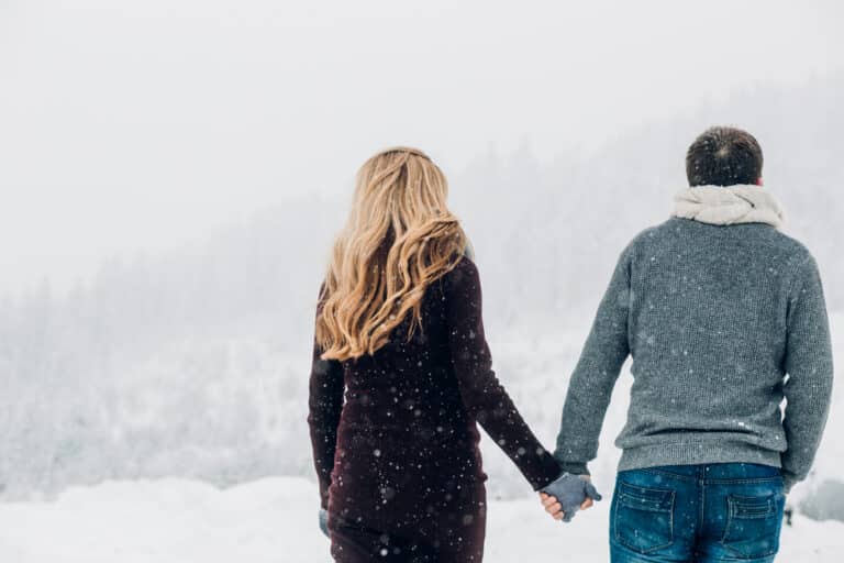 Couple walking in snow holding hands