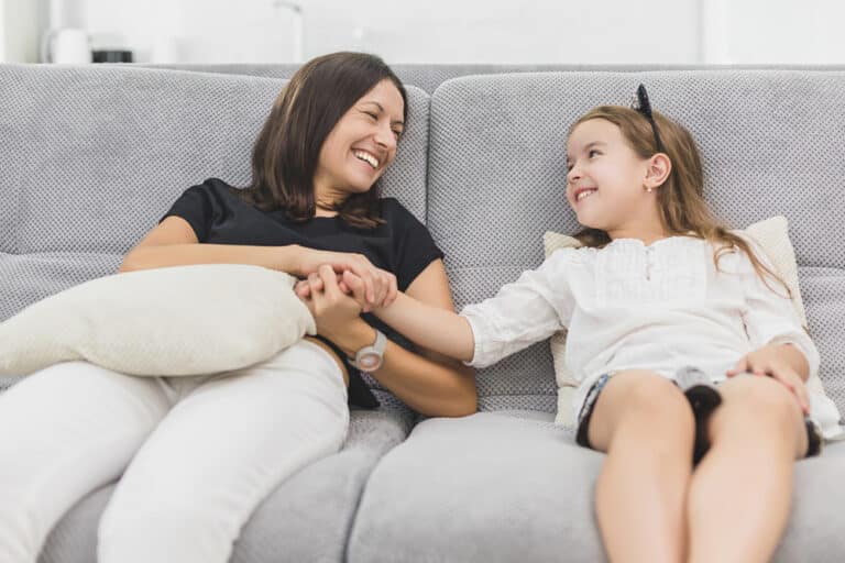 Mother and daughter hold hands on couch