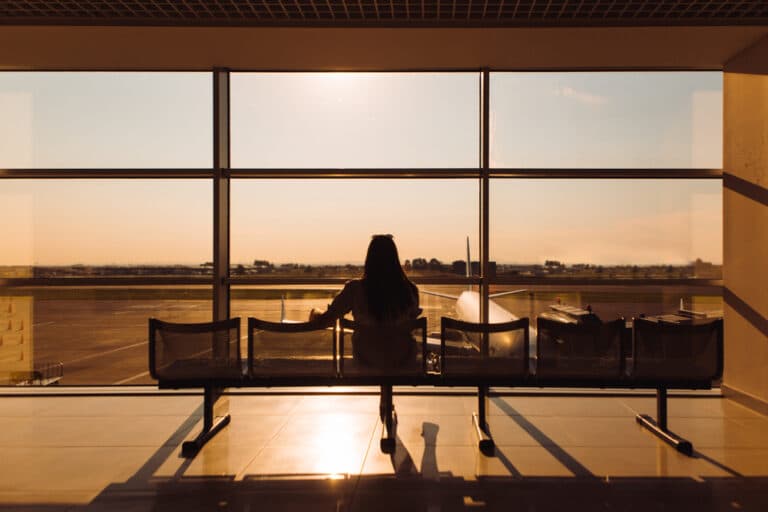 Woman at airport silhouetted against window