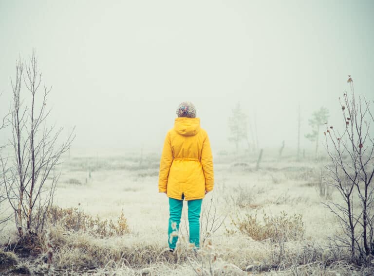 Woman in yellow coat standing in wintery field