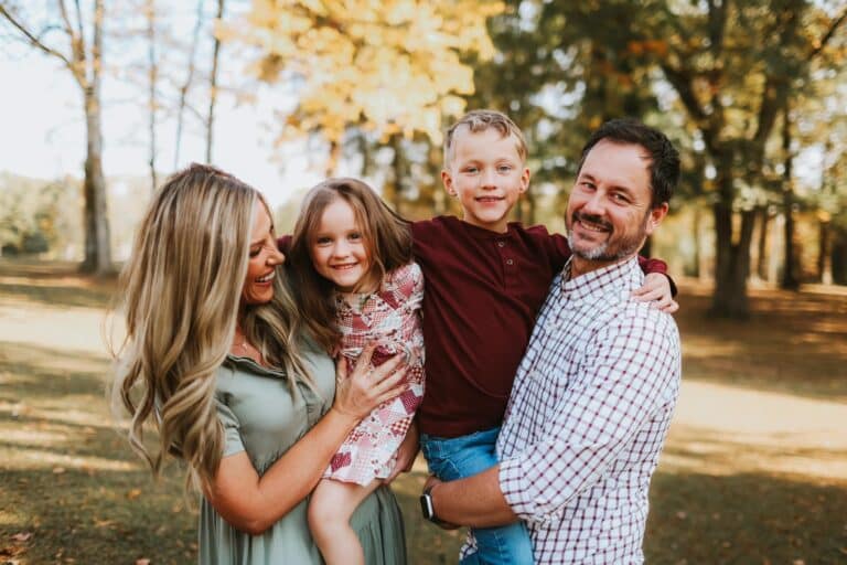 Family of four smiling in posed outdoor photo