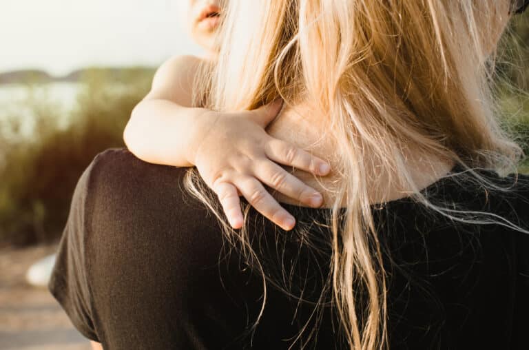 Woman hugging young child, back view