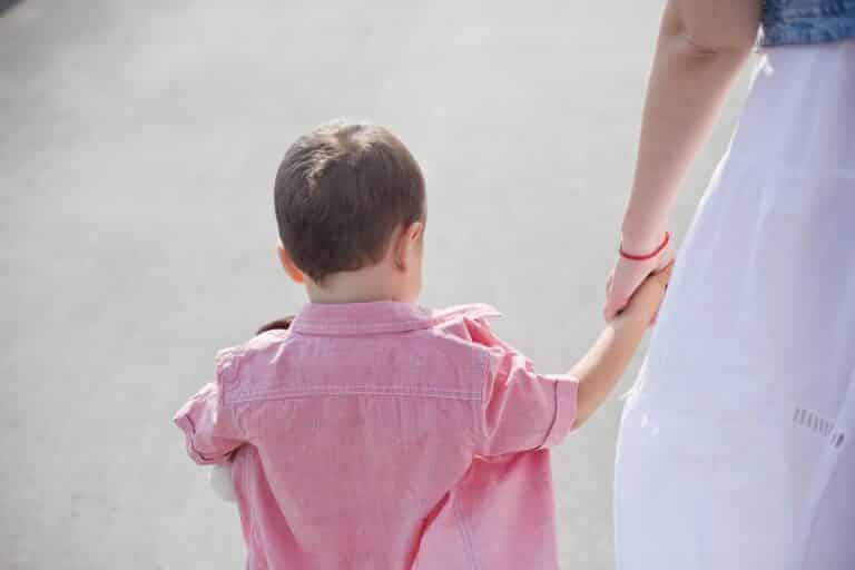 Woman holds little boy's hand