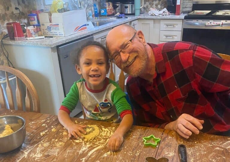 Child and grandfather making cookies together