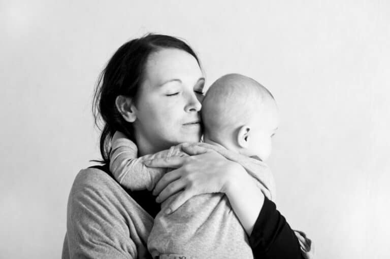 Mother holding baby with eyes closed, black and white image