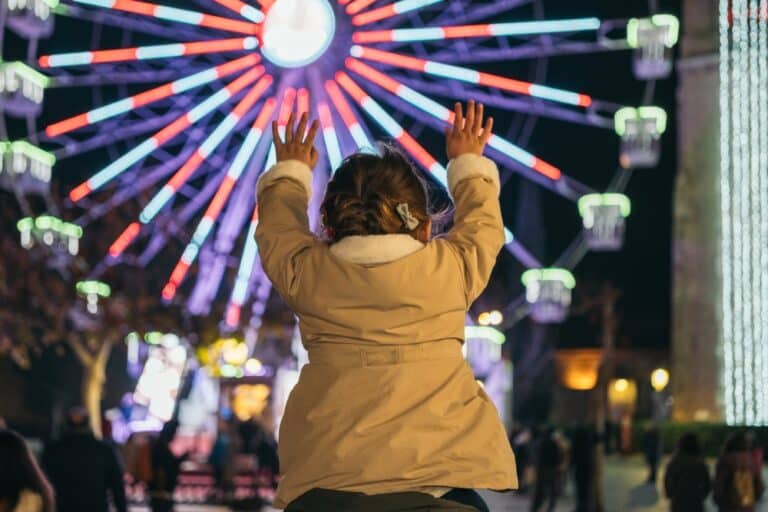 Little girl standing in front of Ferris wheel