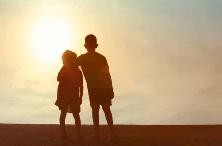Two kids arms around each other, silhouette