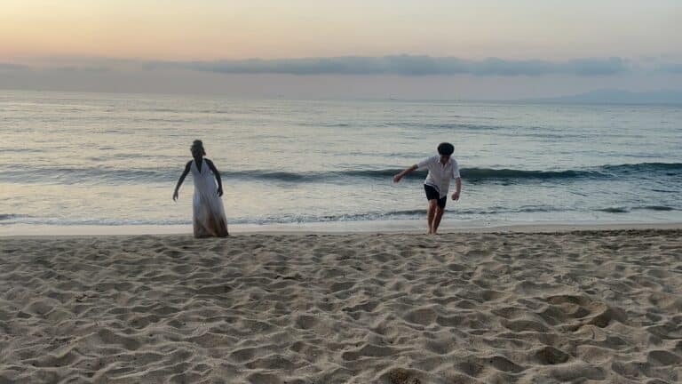 Two people running up from the water at the beach