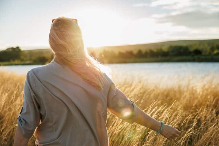 Woman walking in field with hand in wheat
