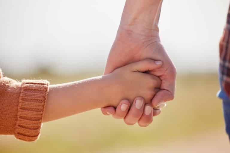 Hand holding young child's hand