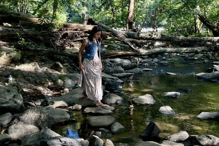 Woman wading in shallow pond with rocks