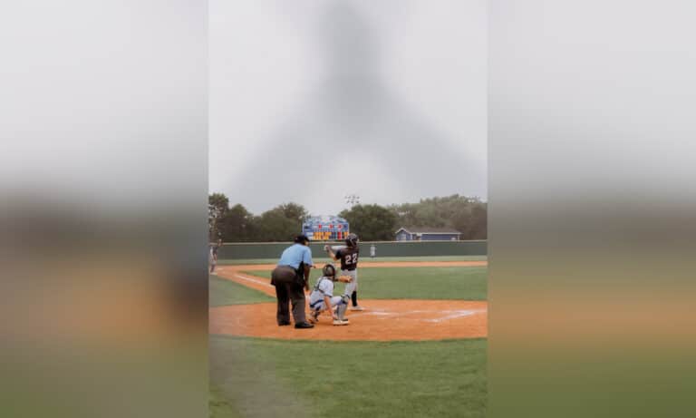Baseball game as seen through the fence behind home plate