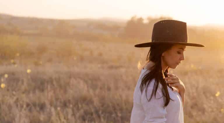 Woman standing in field wearing hat